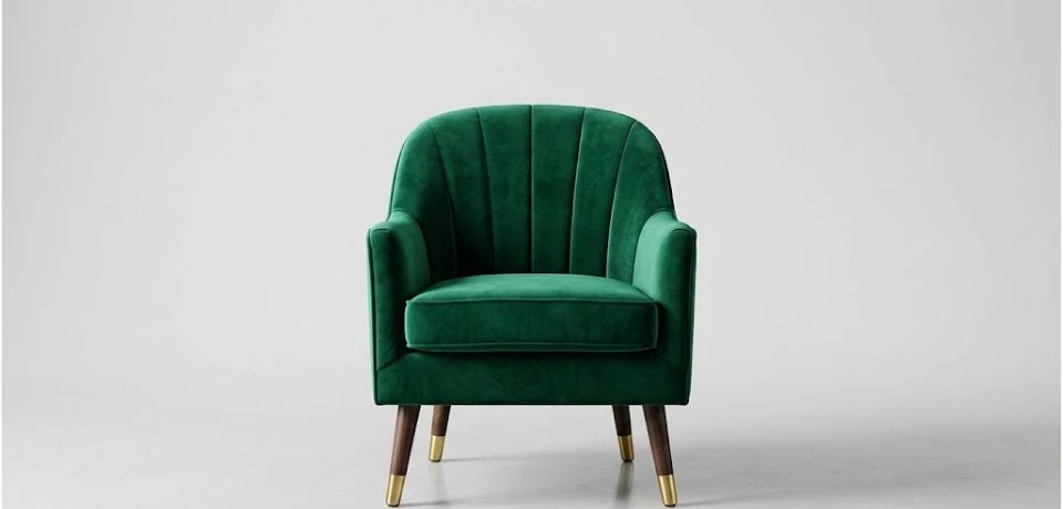 A professionally lit emerald green velvet armchair centered on a neutral gray background.